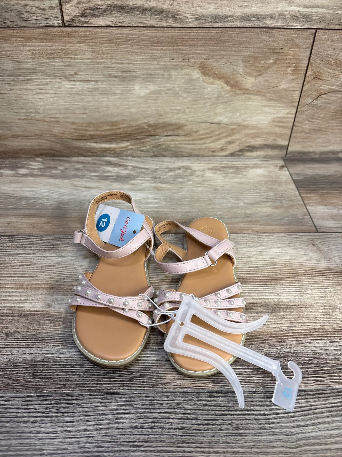 Top-down view of Cat & Jack toddler blush sandals with pearl-adorned straps and Velcro ankle strap, size 12 tag on wood floor