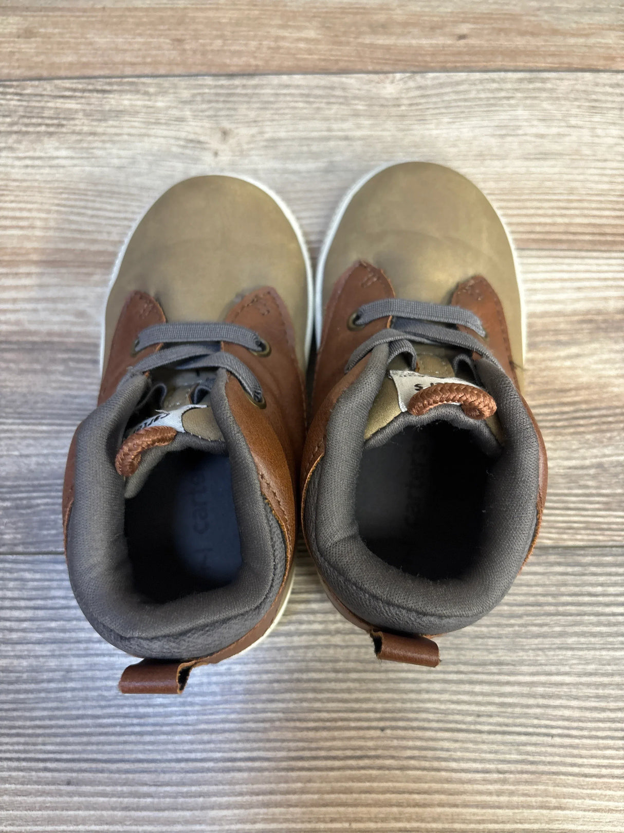Brown and tan toddler shoes with gray laces on wood floor, gently used kids footwear