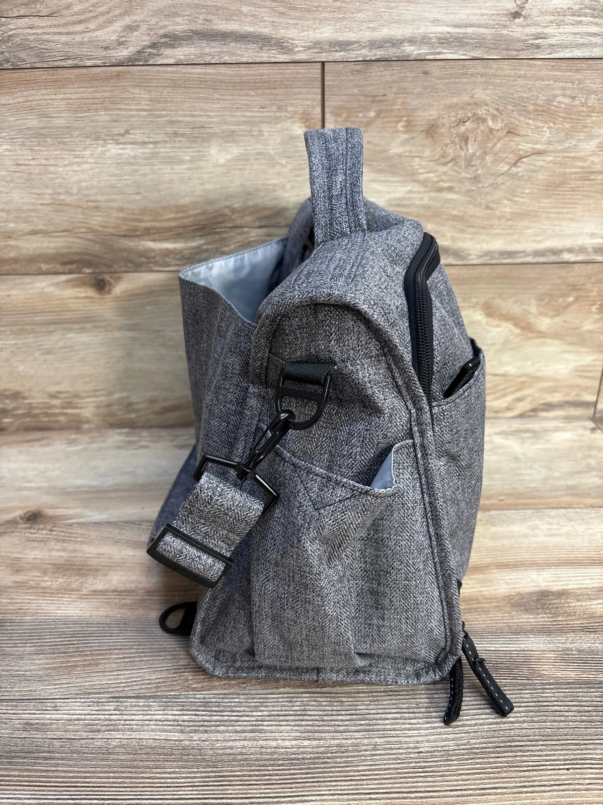 Gray herringbone backpack with side pockets on wooden floor background