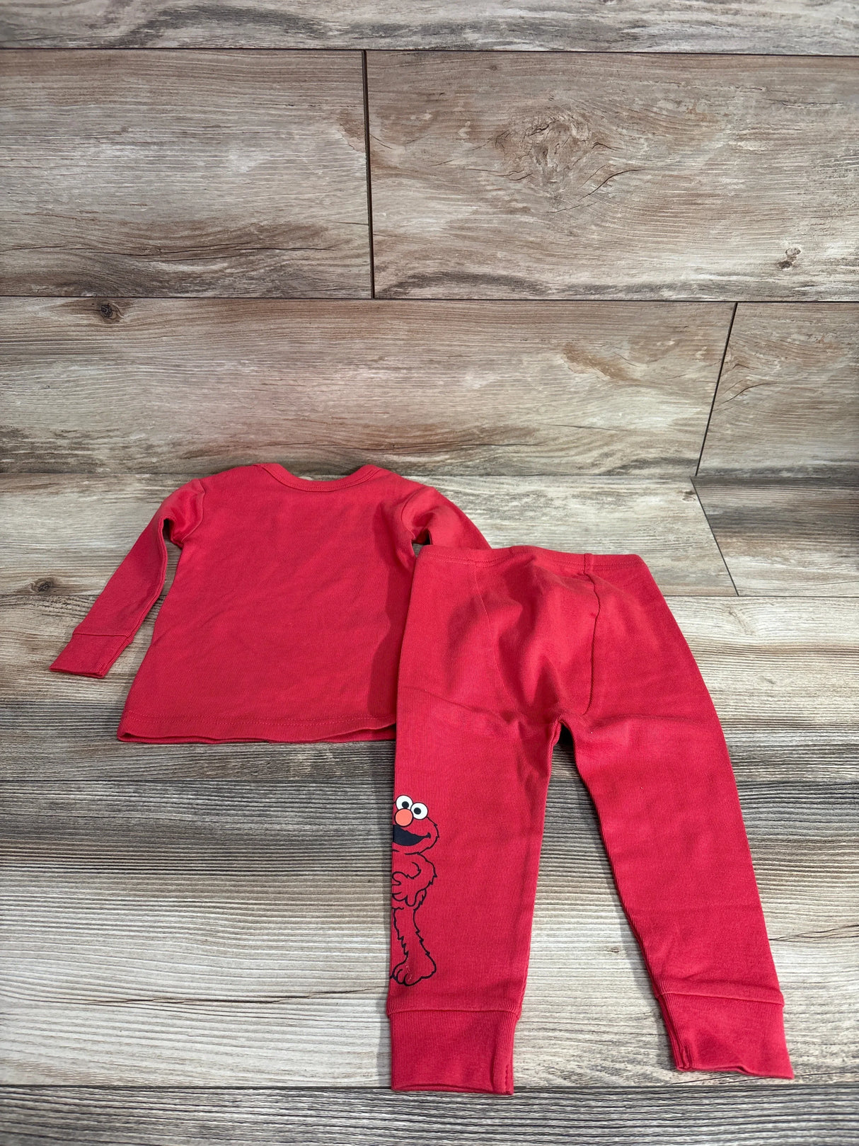 Flat lay of red Baby Gap Elmo organic brushed cotton pajama set 12-18 months showing Elmo on pant leg on wood background