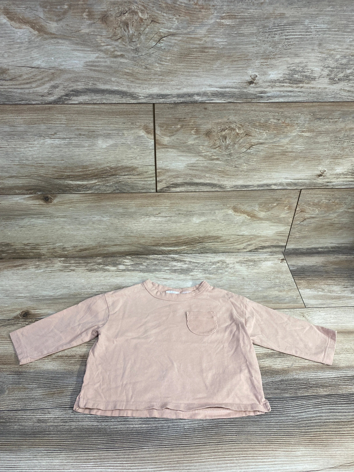 Light pink long sleeve toddler shirt with chest pocket on wood background