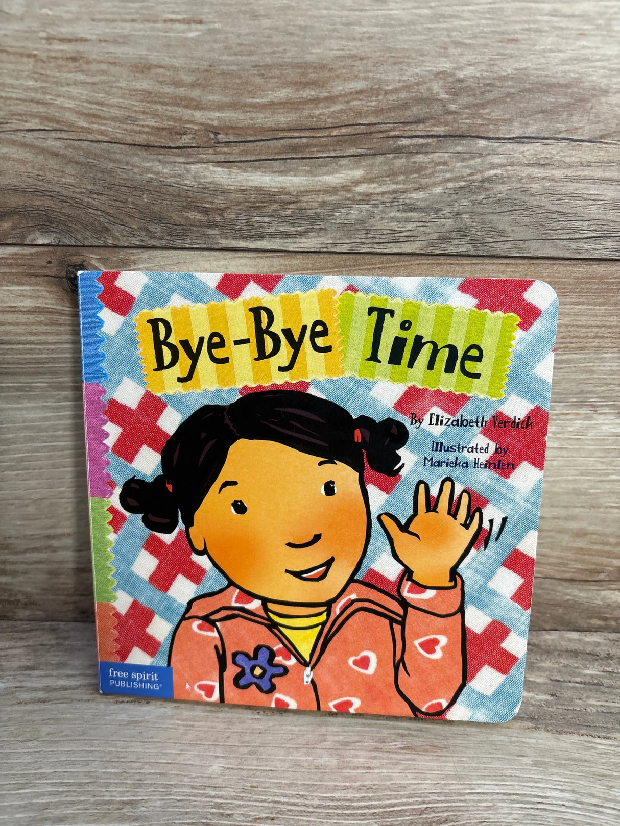 Bye-Bye Time children's book cover on wood, illustrated girl waving, Free Spirit Publishing