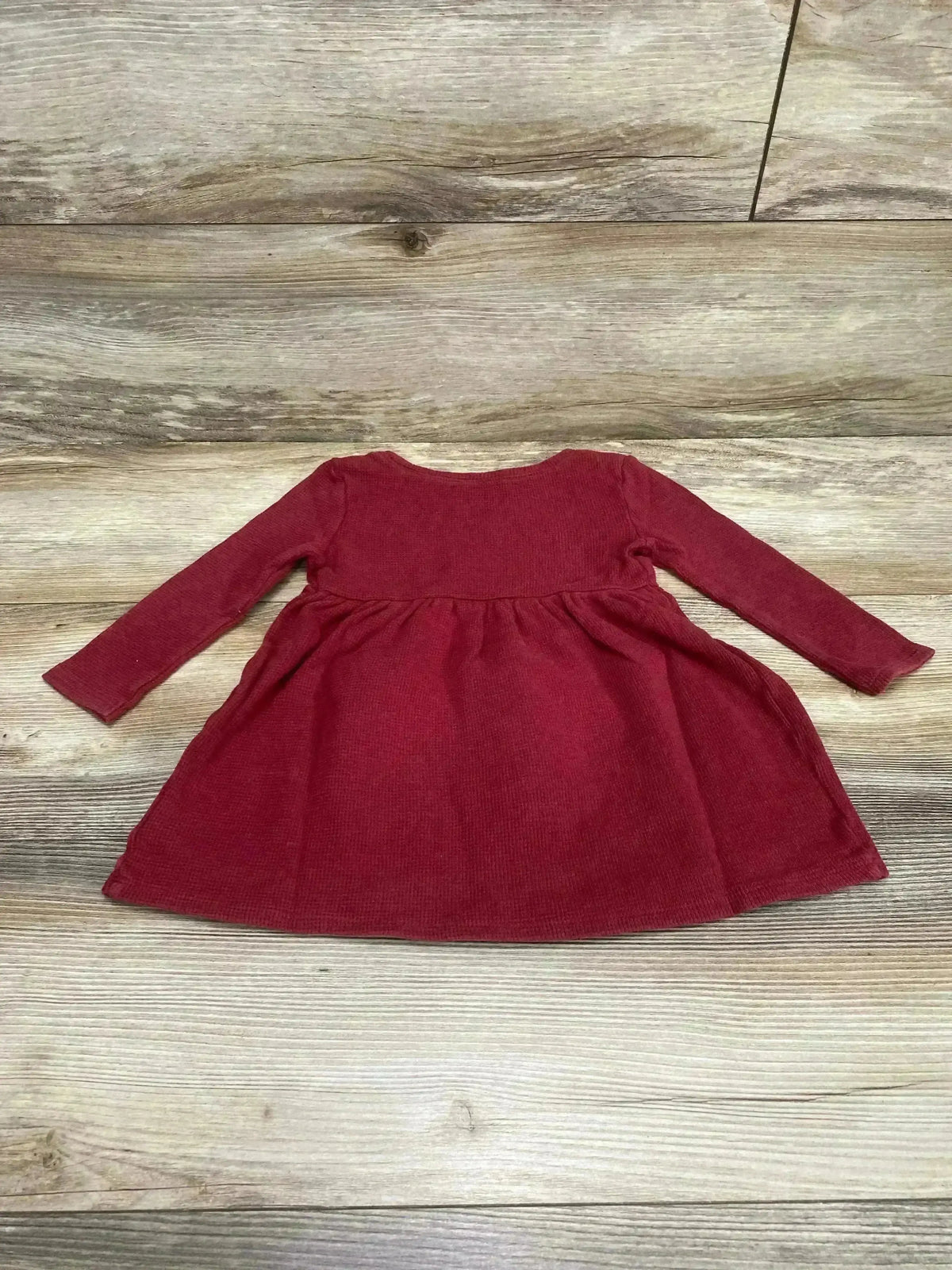 Flat lay of red Old Navy thermal toddler dress 18 to 24 months showing long sleeves and gathered skirt on wood background