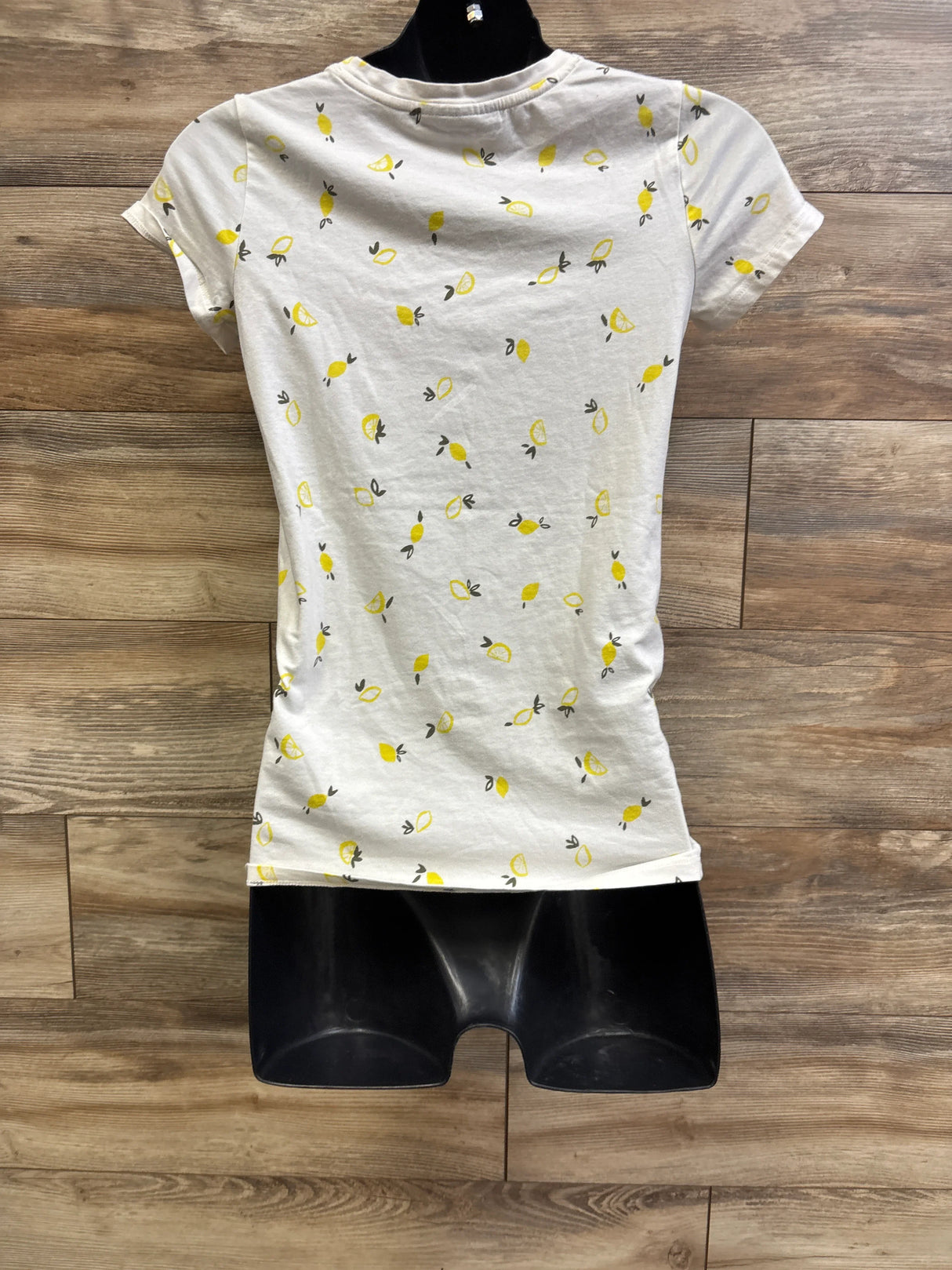 Front view of A Pea In The Pod maternity short-sleeve shirt with all-over yellow lemon print on white, wood plank background