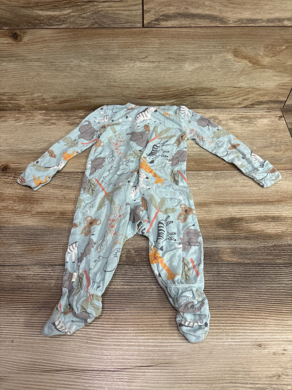 Flat-lay view of Huggies blue sleeper in size 3 months showcasing long sleeves and animal print on a wood background