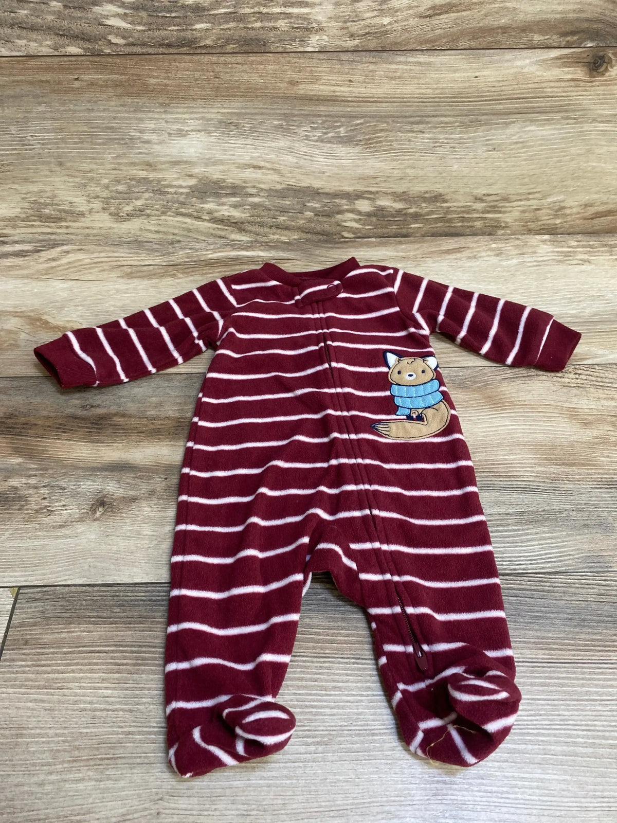 Maroon striped baby sleeper with fox patch, long sleeves, and footed design on wood floor