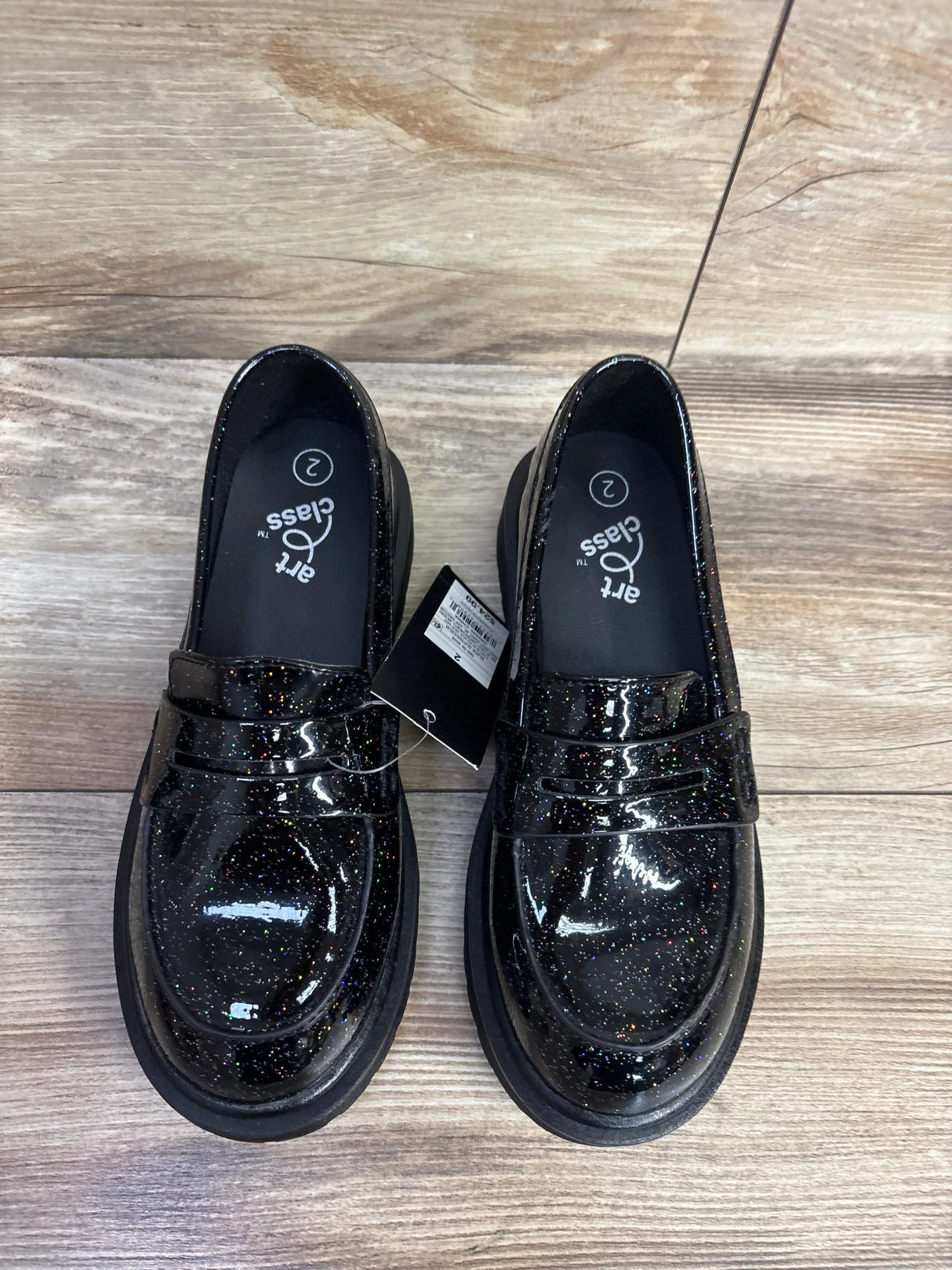 Black glittery kids loafers with patent finish on wood floor, size 2, new with tag