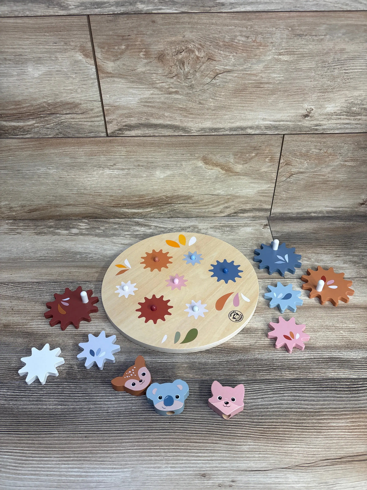 Overhead view of Speedy Monkey Wooden Gear Toy showcasing colorful wooden gears and animal pieces on a wood-look floor