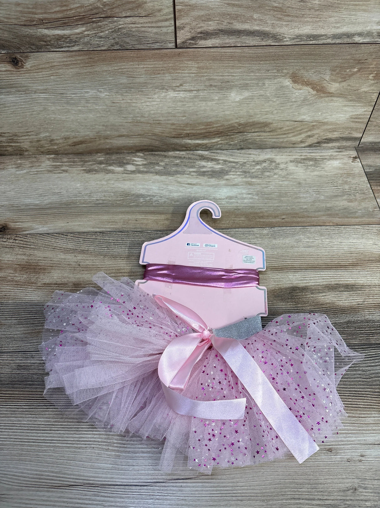 Pink glittery toddler tutu skirt with satin ribbon bow and matching headband on wooden floor