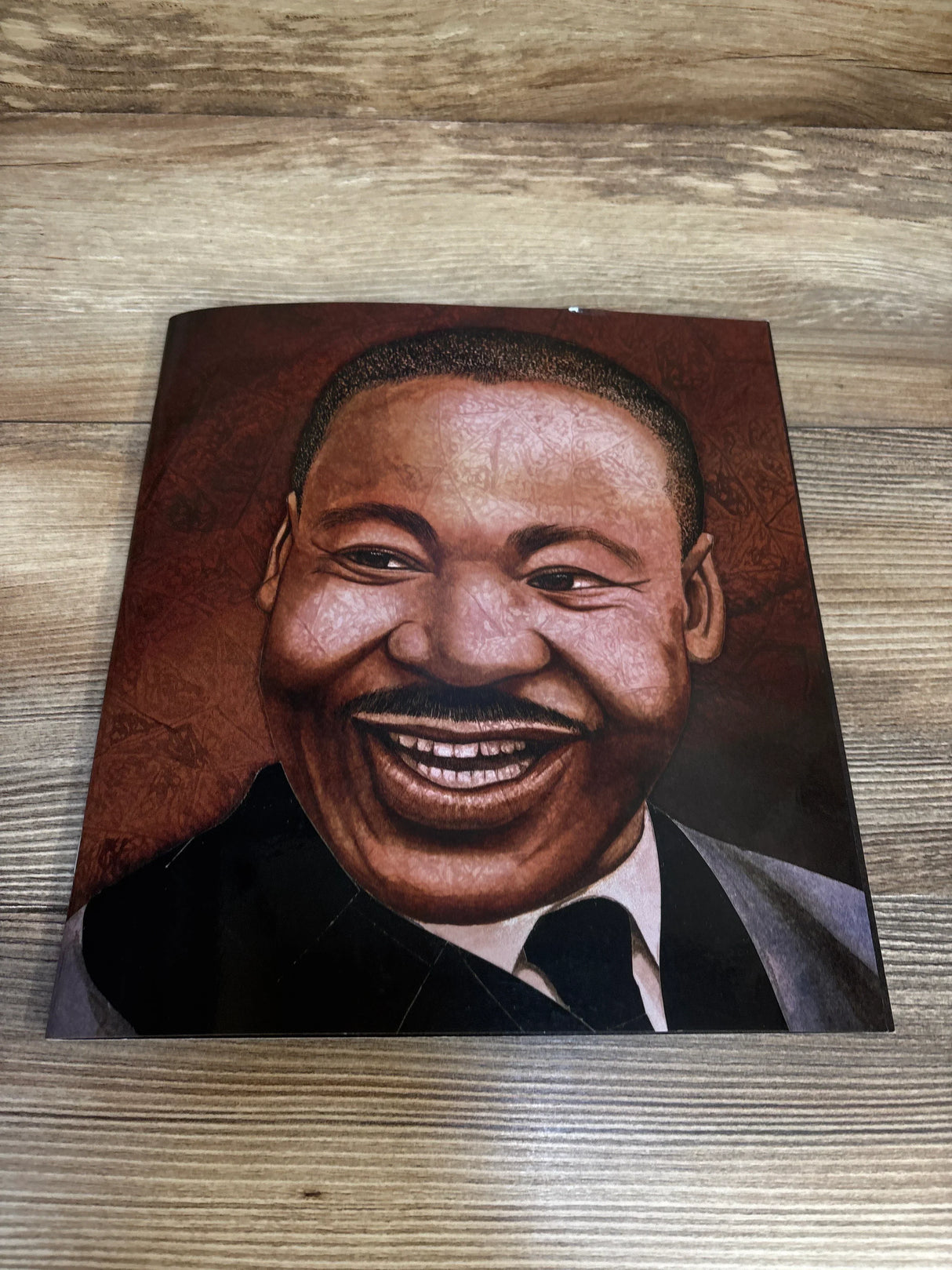 Front view of Martin’s Big Words paperback showing large illustrated smiling portrait of Dr. Martin Luther King Jr. on a wooden surface