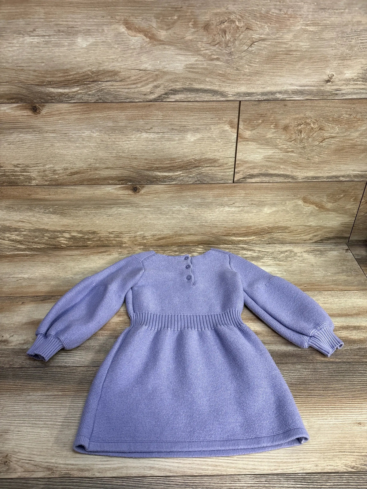 Lilac long sleeve knitted baby dress with buttons on wooden floor background