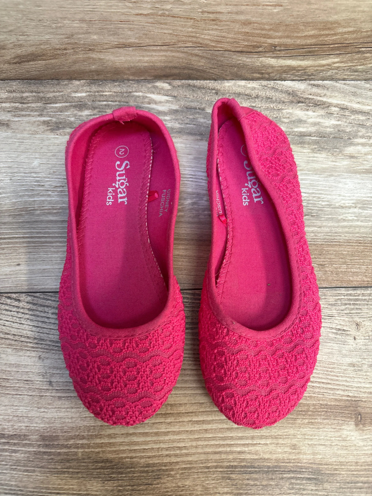 Top view of Sugar Kids lace ballet flats in pink (size 2Y) showcasing lace texture and branded insoles on wood floor