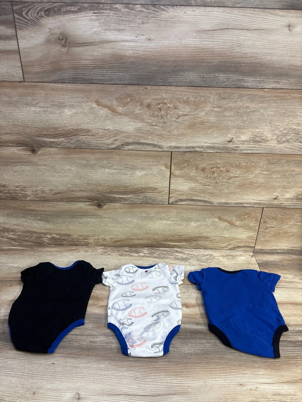 Champion 3-pack baby bodysuit set in black, white with logo print, and blue, size 3m.