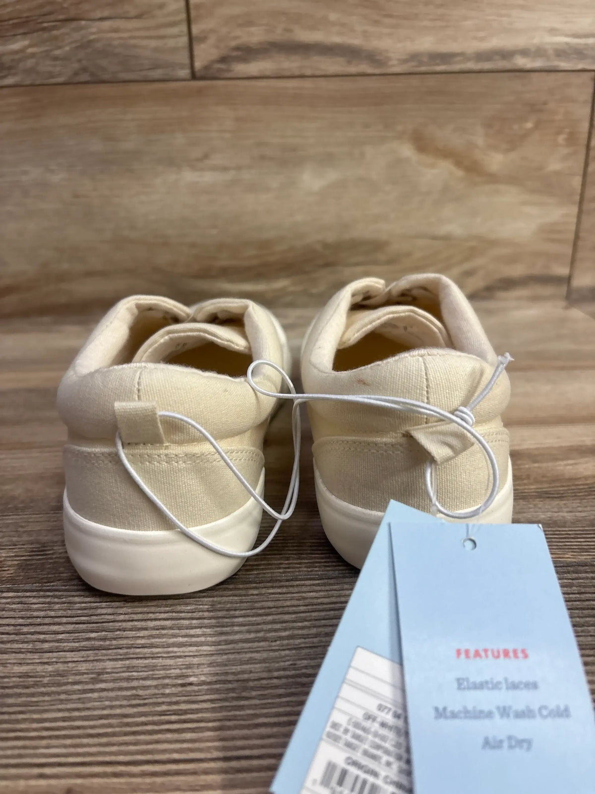 Back view of Cat & Jack Tyler slip-on toddler sneakers size 4Y showcasing off-white canvas and elastic laces with attached tags on wood floor