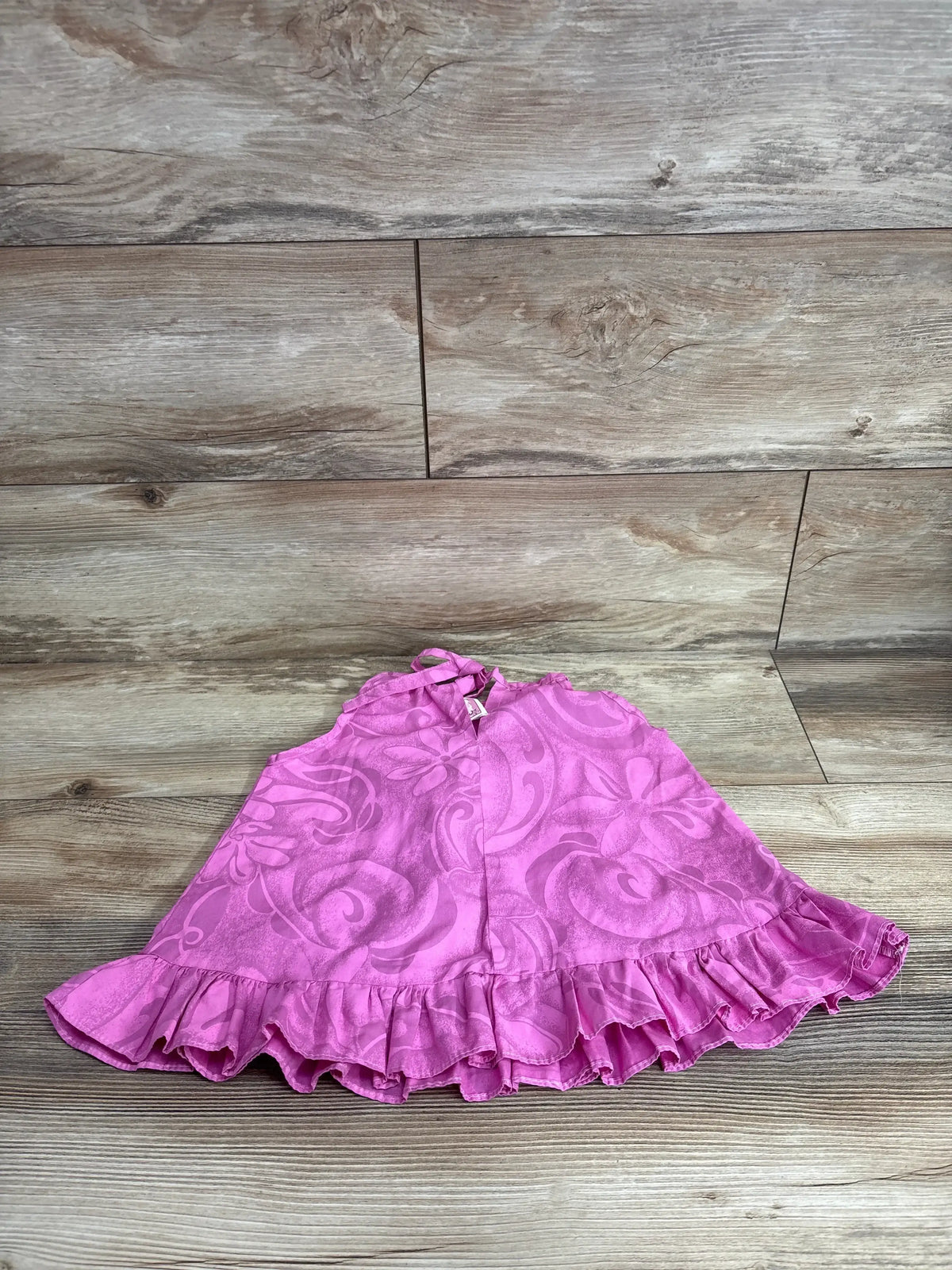 Front view of RJC Floral Halter Dress in pink showcasing tonal hibiscus print halter tie and ruffled hem on wood plank floor