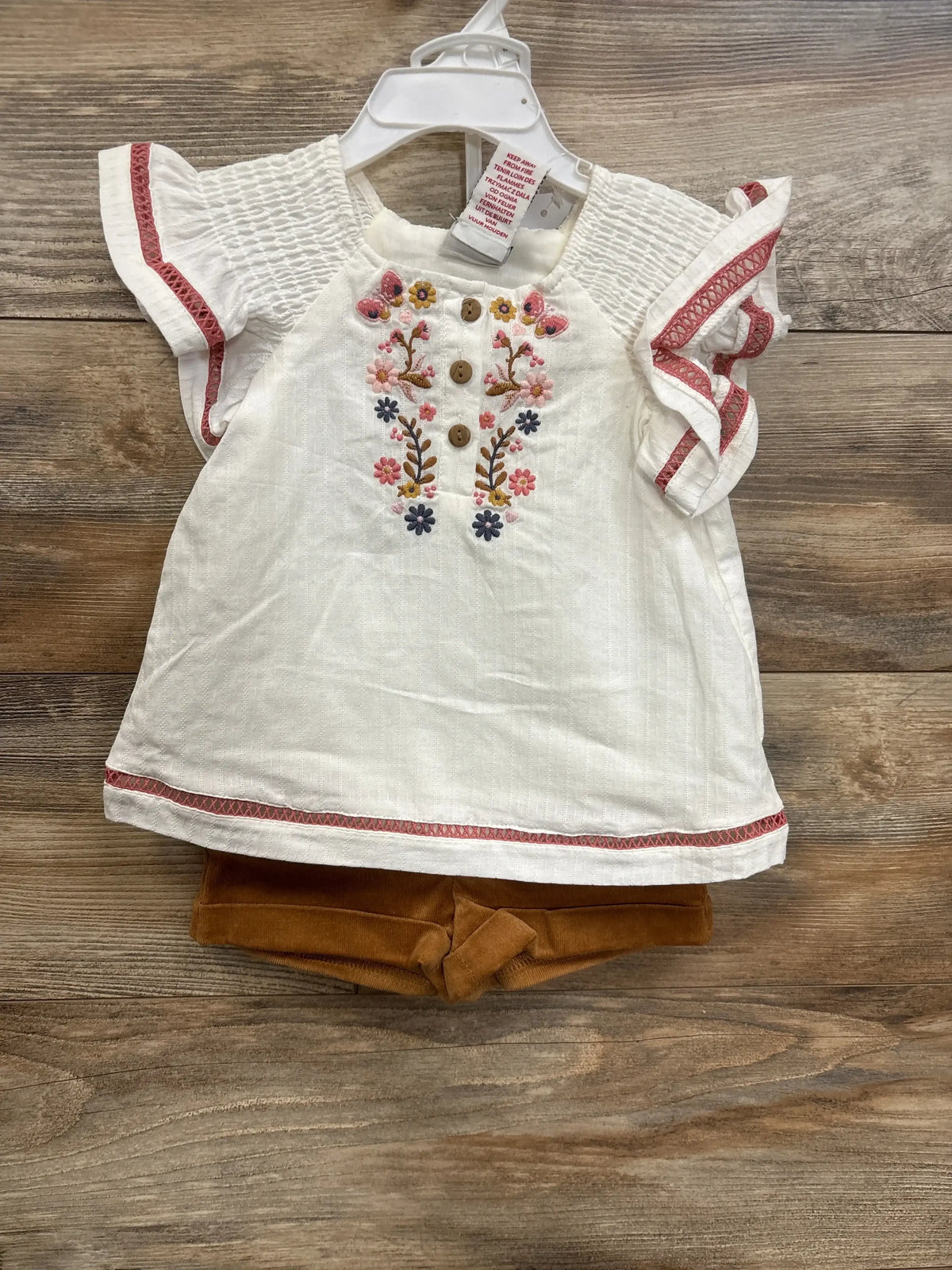 Front view of white Haute Hippie 3pc layette set showcasing floral embroidery, smocked sleeves, and corduroy shorts