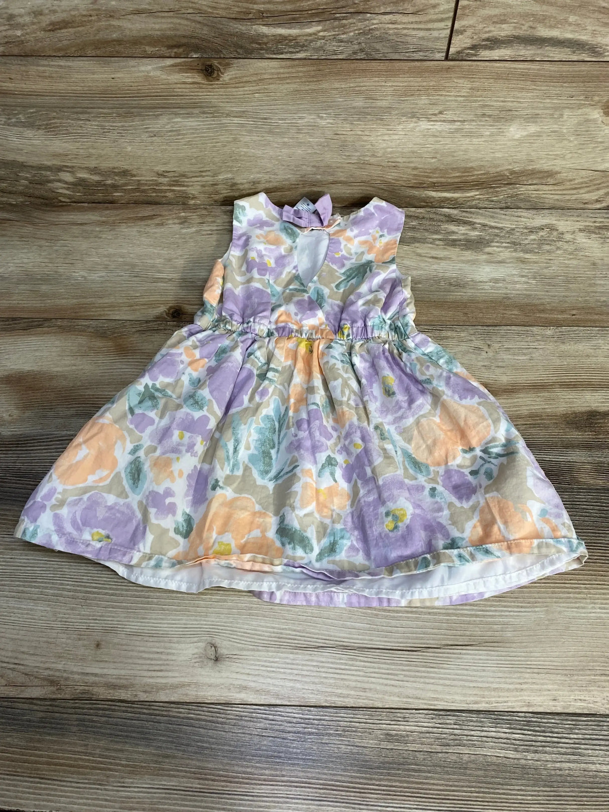 Front view of Carter’s Floral Dress size 3T in white with pastel lavender peach and green floral print on a wood plank background