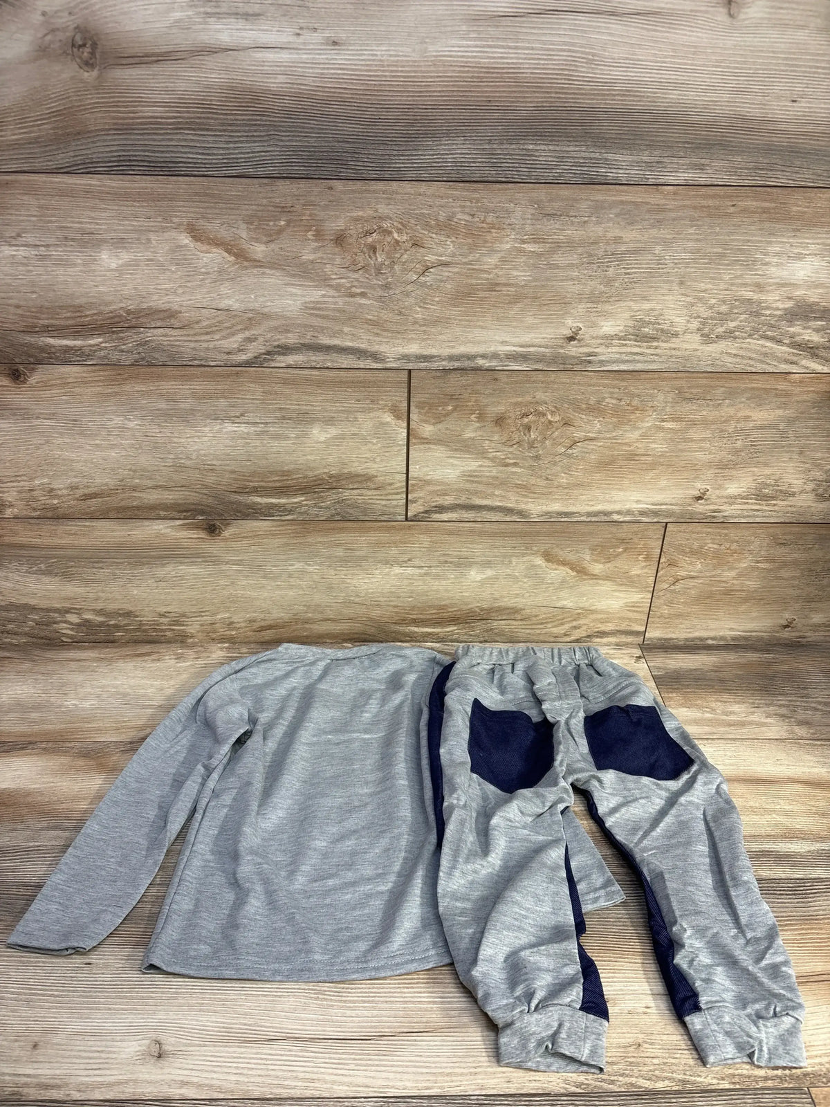 Children's gray long sleeve shirt and matching pants with navy blue pockets on wood floor