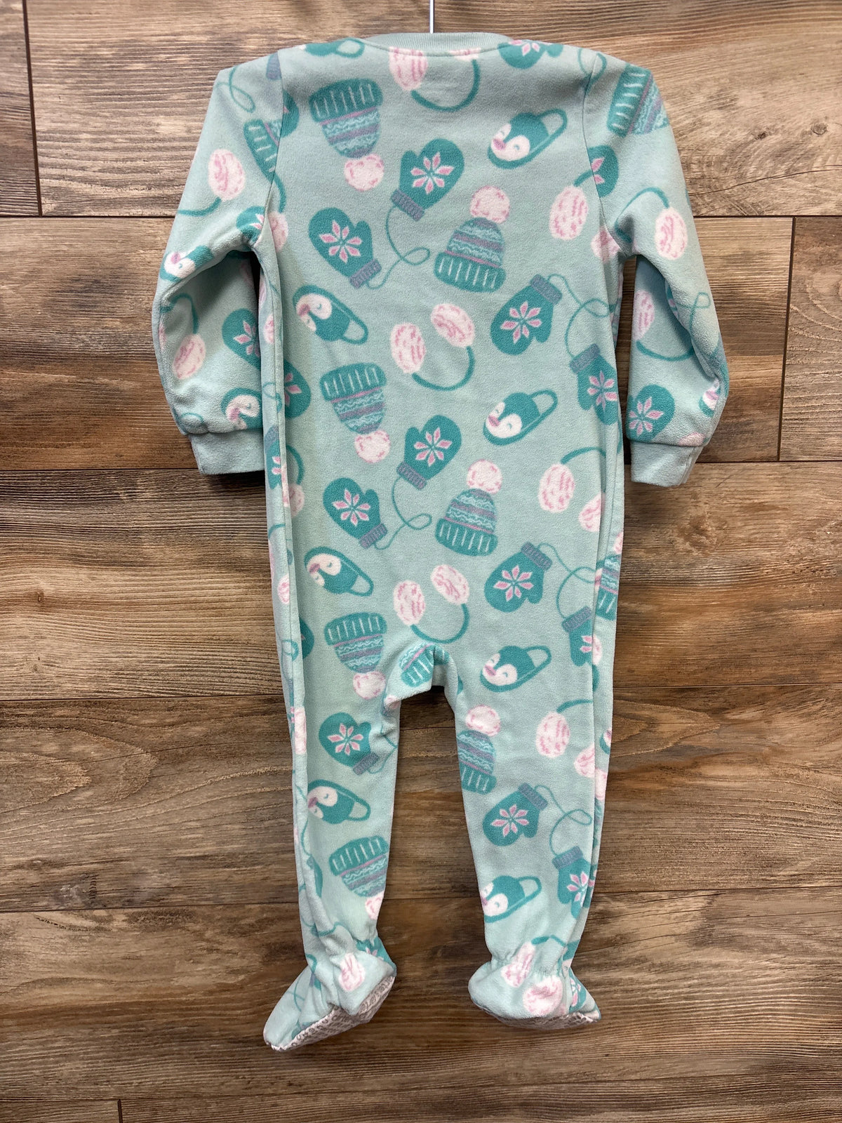 Front view of Just One You winter blanket sleeper in blue, showcasing long sleeves, covered feet, and winter pattern on wood