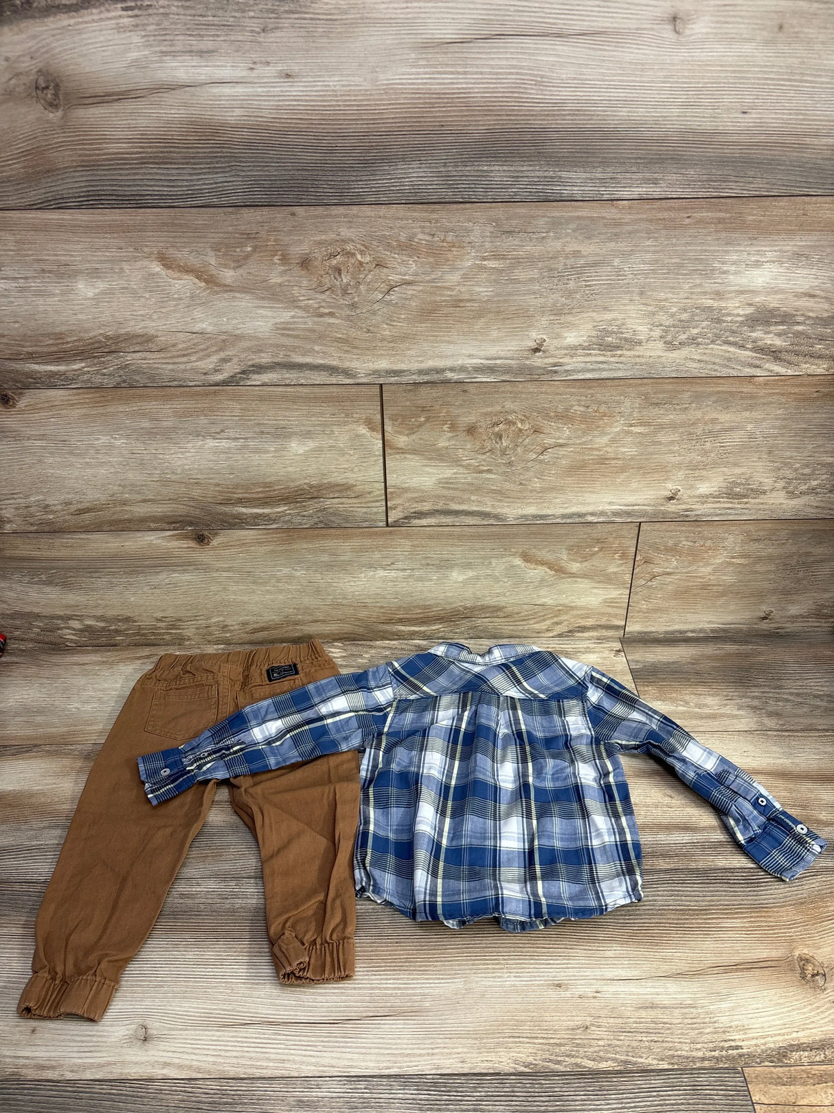 Flat lay of Ben Sherman 2pc Plaid Button Up Shirt and Pants Set in blue size 24m showcasing blue plaid shirt and brown jogger pants on wood plank floor