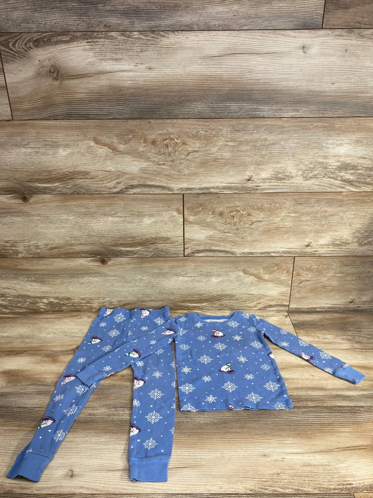 Blue children's pajama set with polar bear and snowflake winter print on wooden floor
