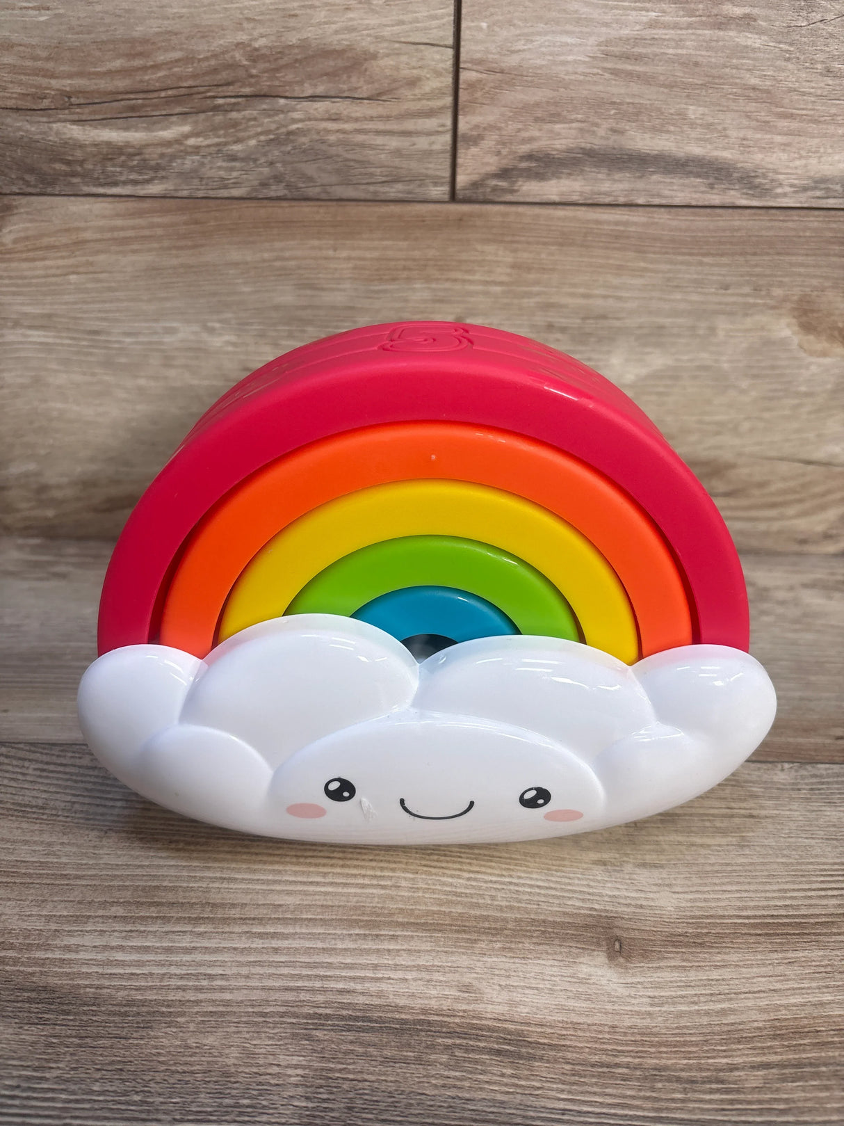 Colorful rainbow stacking toy with smiling cloud, wooden background, kids toy resale