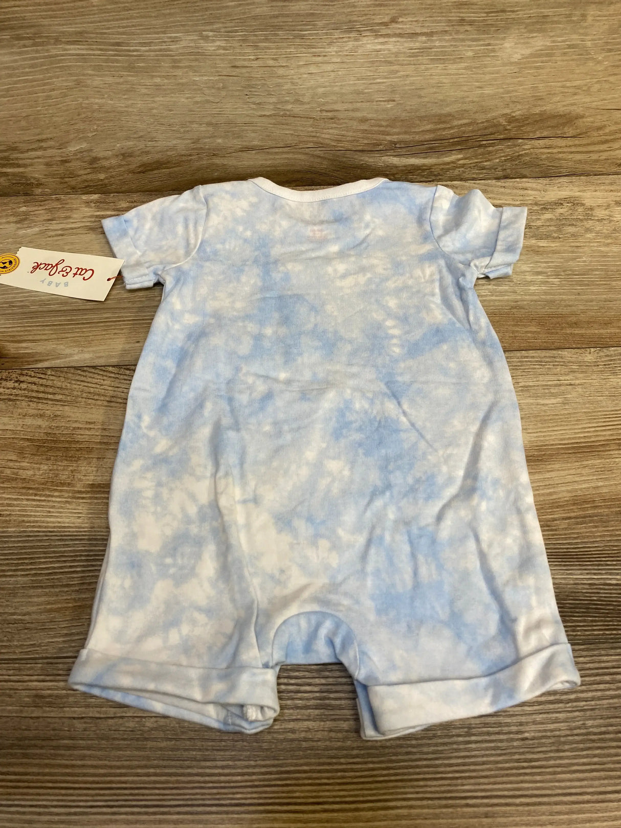 Back view of Cat and Jack baby romper, light blue tie-dye, short sleeves with rolled cuffs on wood floor, size 3-6 months