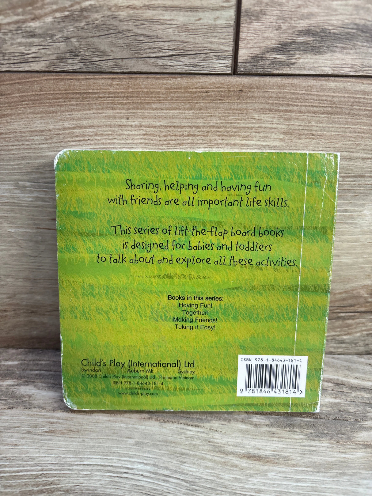 Back cover of a Child's Play International board book on wood background, text and barcode visible.