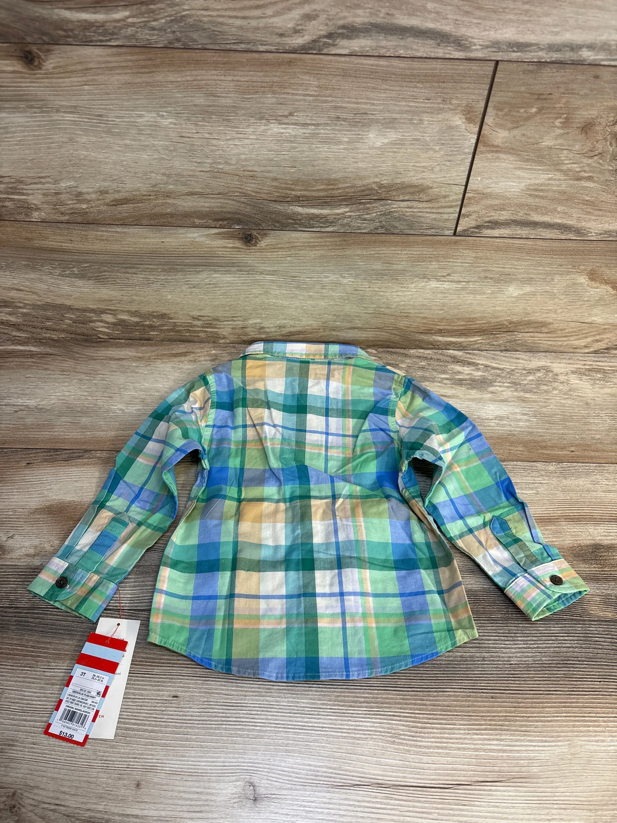 Green and blue plaid toddler shirt with long sleeves, laid on wood floor, size 3T tag visible