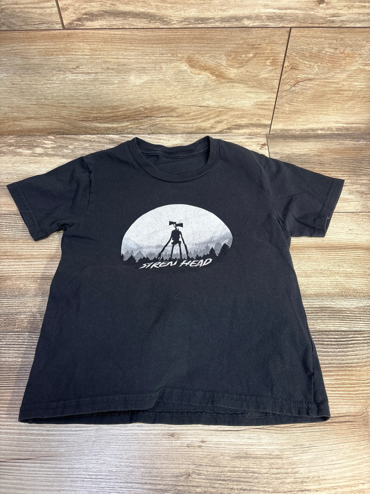 Front view of black Siren Head shirt in size 5/6T showcasing its graphic and short sleeves with a wood patterned floor