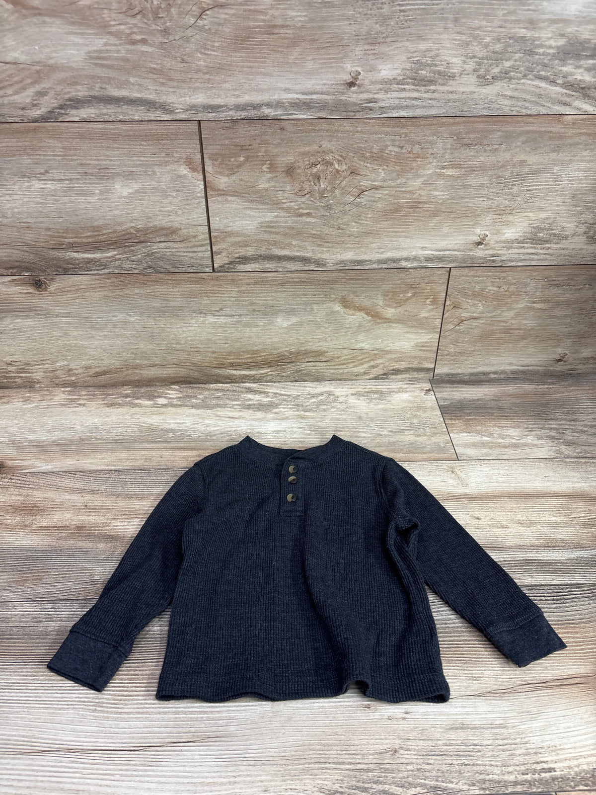 Top-down view of Old Navy gray waffle knit Henley shirt showcasing three-button placket and long sleeves on a wood floor