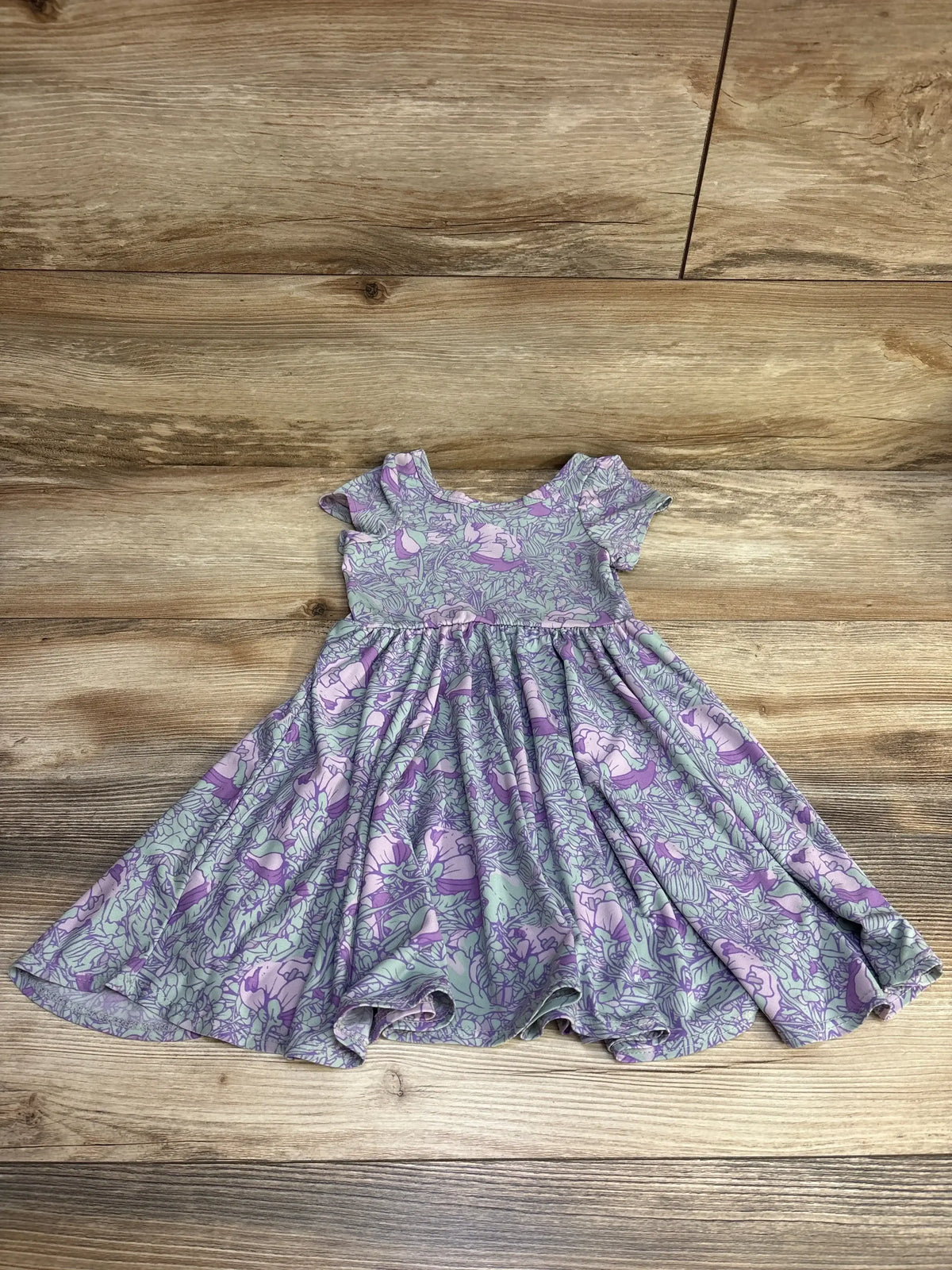 Flat lay of purple floral toddler dress (2T) showing short sleeves, scoop neckline and gathered twirl skirt on wood floor