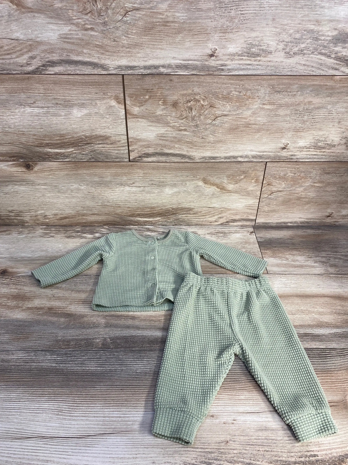 Top view of Rabbit Moon green two-piece set for 0 to 3 months showcasing textured shirt and pants on a wooden background