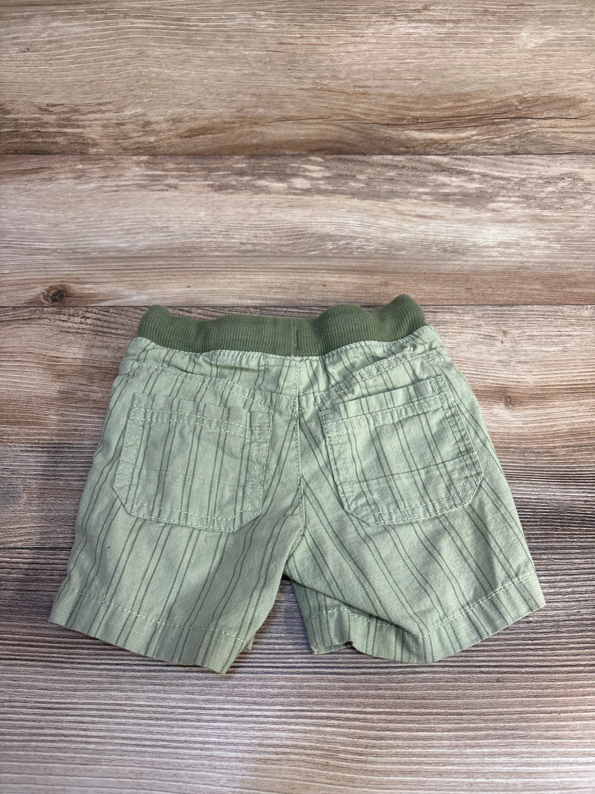 Green striped toddler shorts with two back pockets on a wooden background