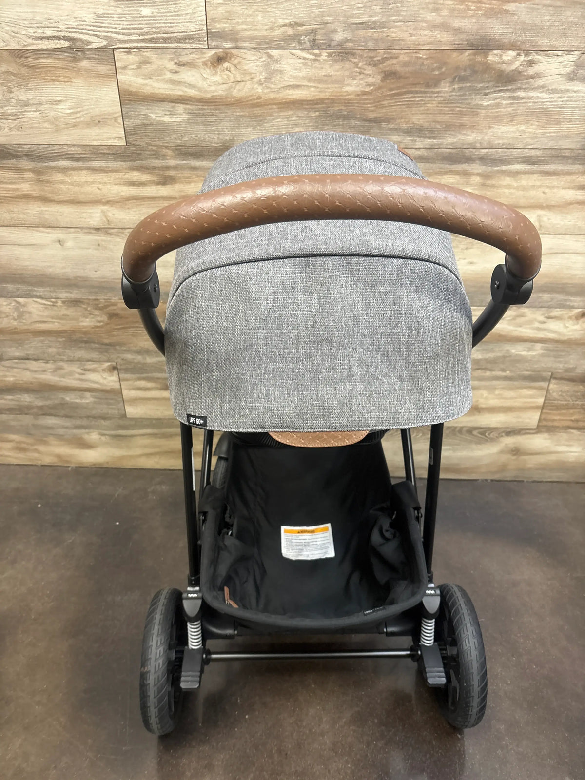 Front view of Chicco Corso Primo stroller in Summit showcasing gray canopy, brown handle, and black seat on wood flooring
