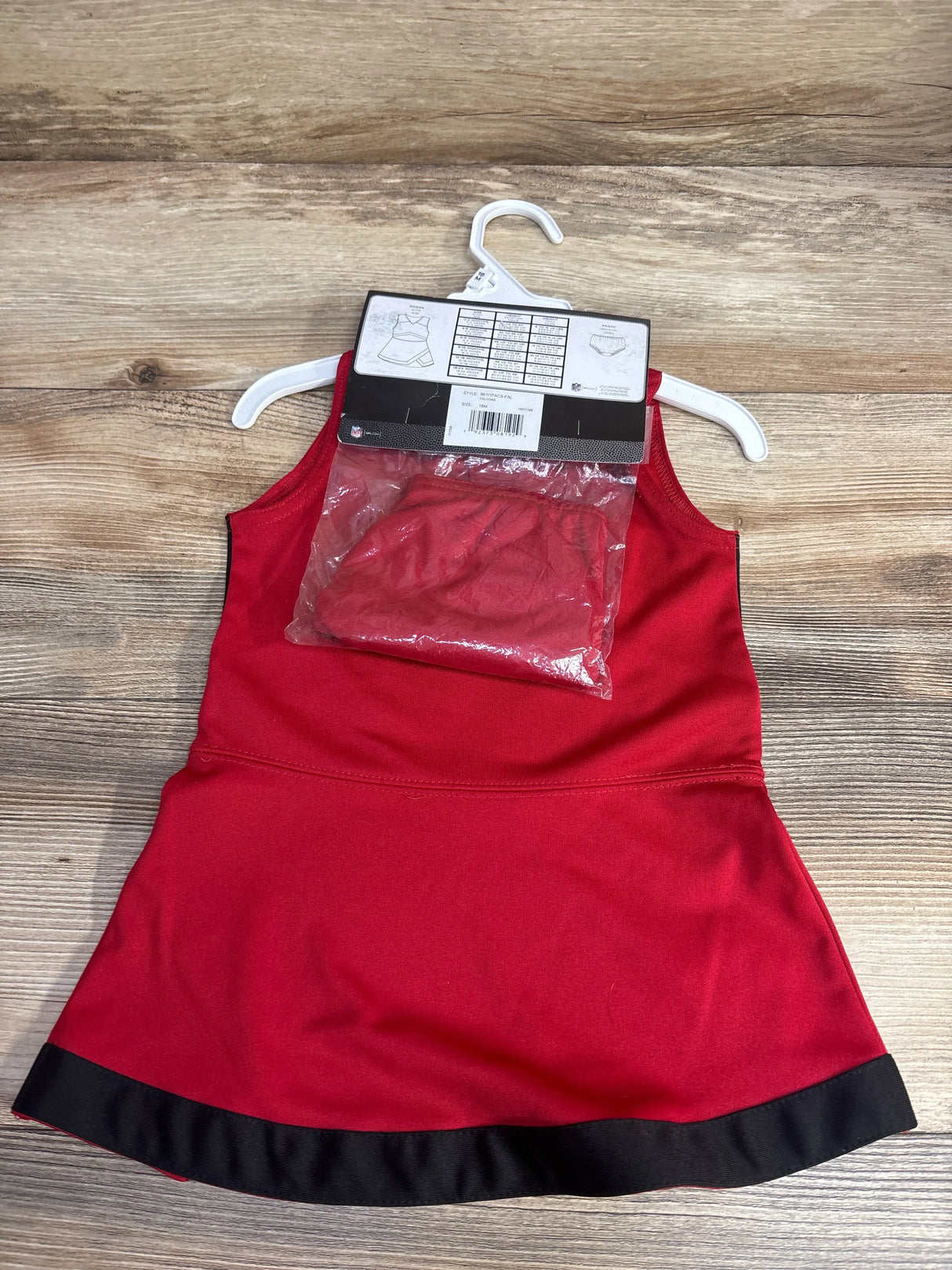 Red and black toddler cheerleader dress with matching red shorts on white hanger on wooden floor