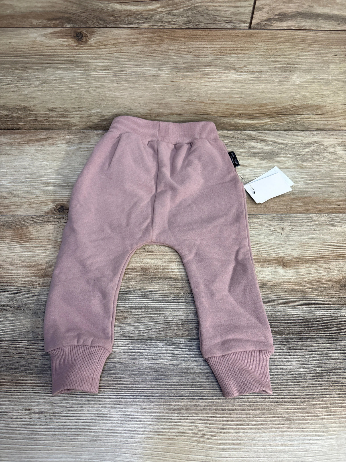 Pink infant pants with ribbed cuffs and waistband on wooden background