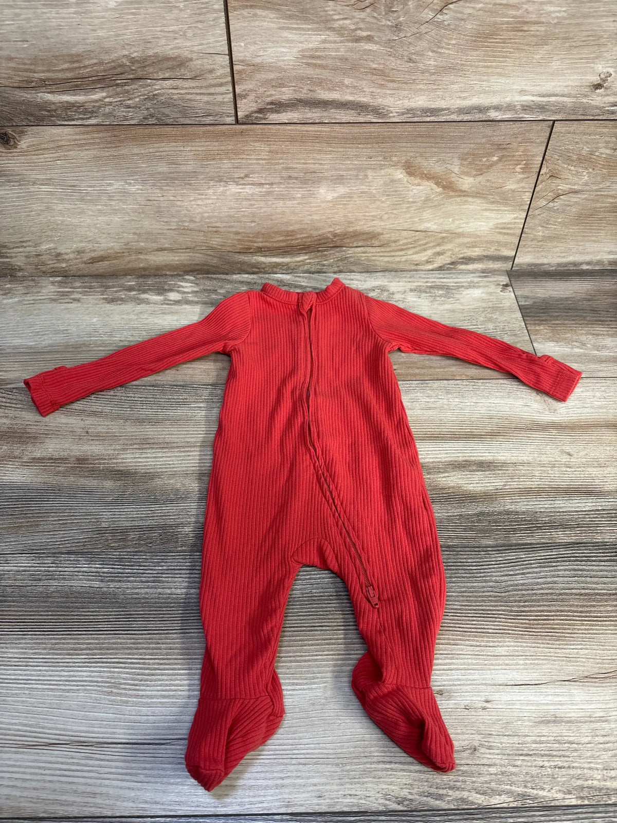 Front view of Old Navy red ribbed sleeper showcasing two-way zipper with wood-grain background