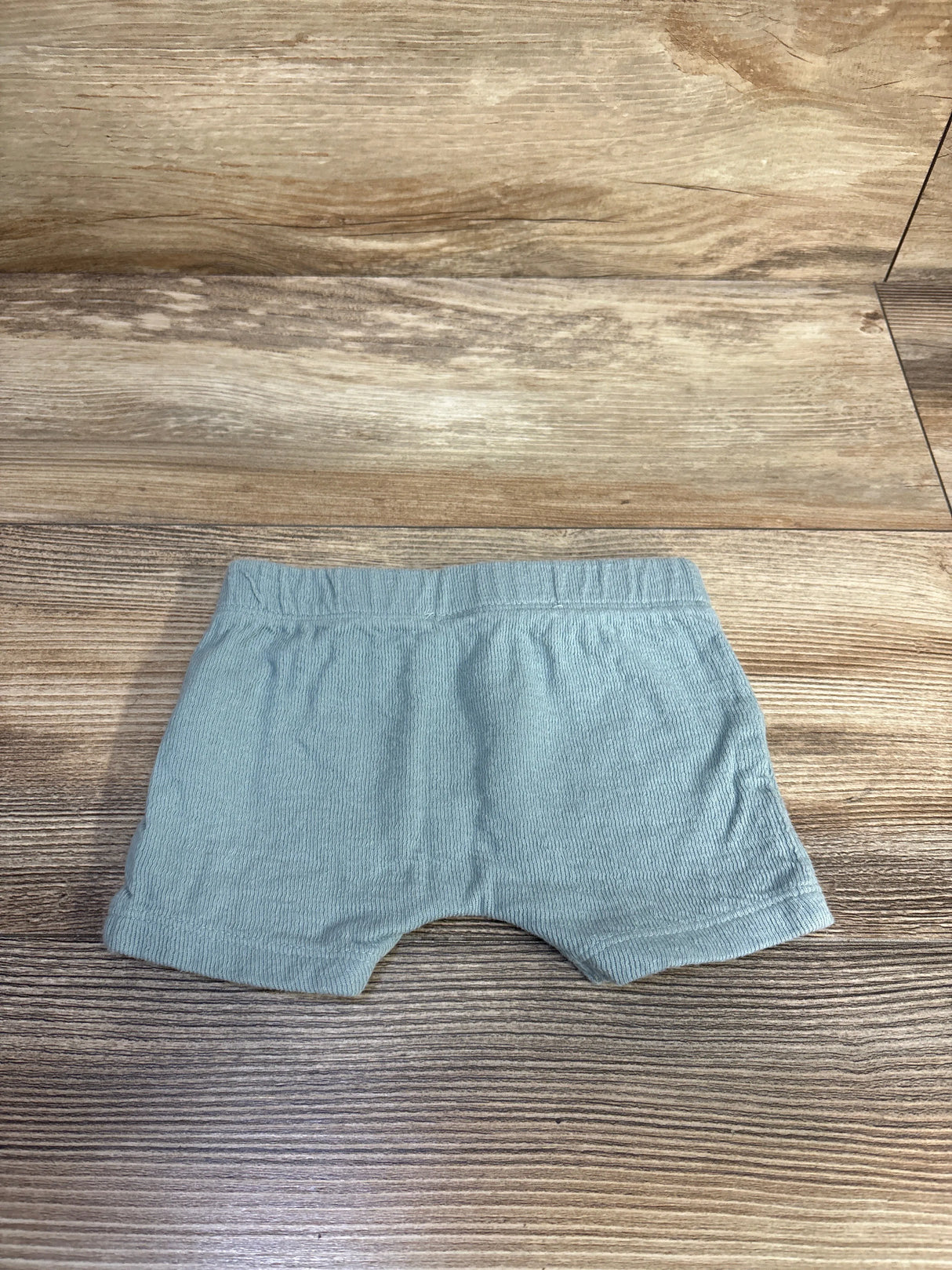 Top down view of blue drawstring shorts showing ribbed fabric and elastic waistband on wood background