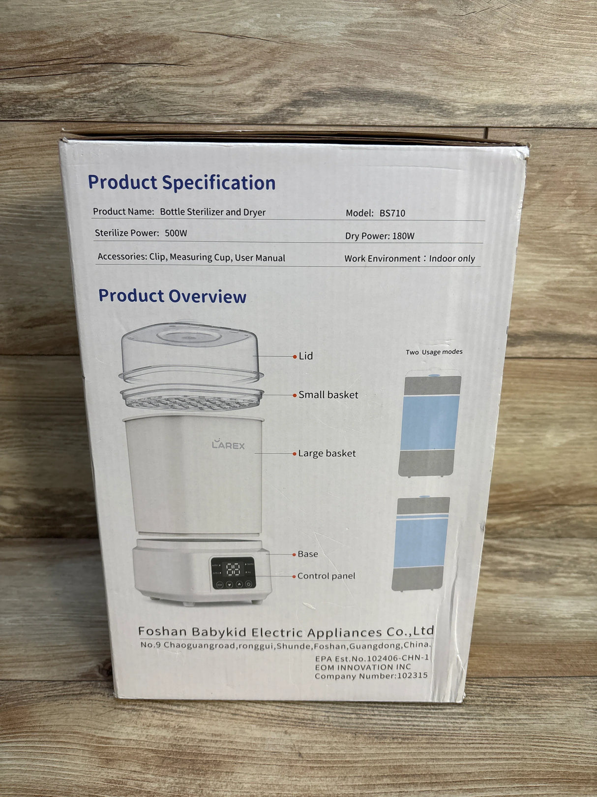 Box of baby bottle sterilizer and dryer with product specifications and diagram on wood background.