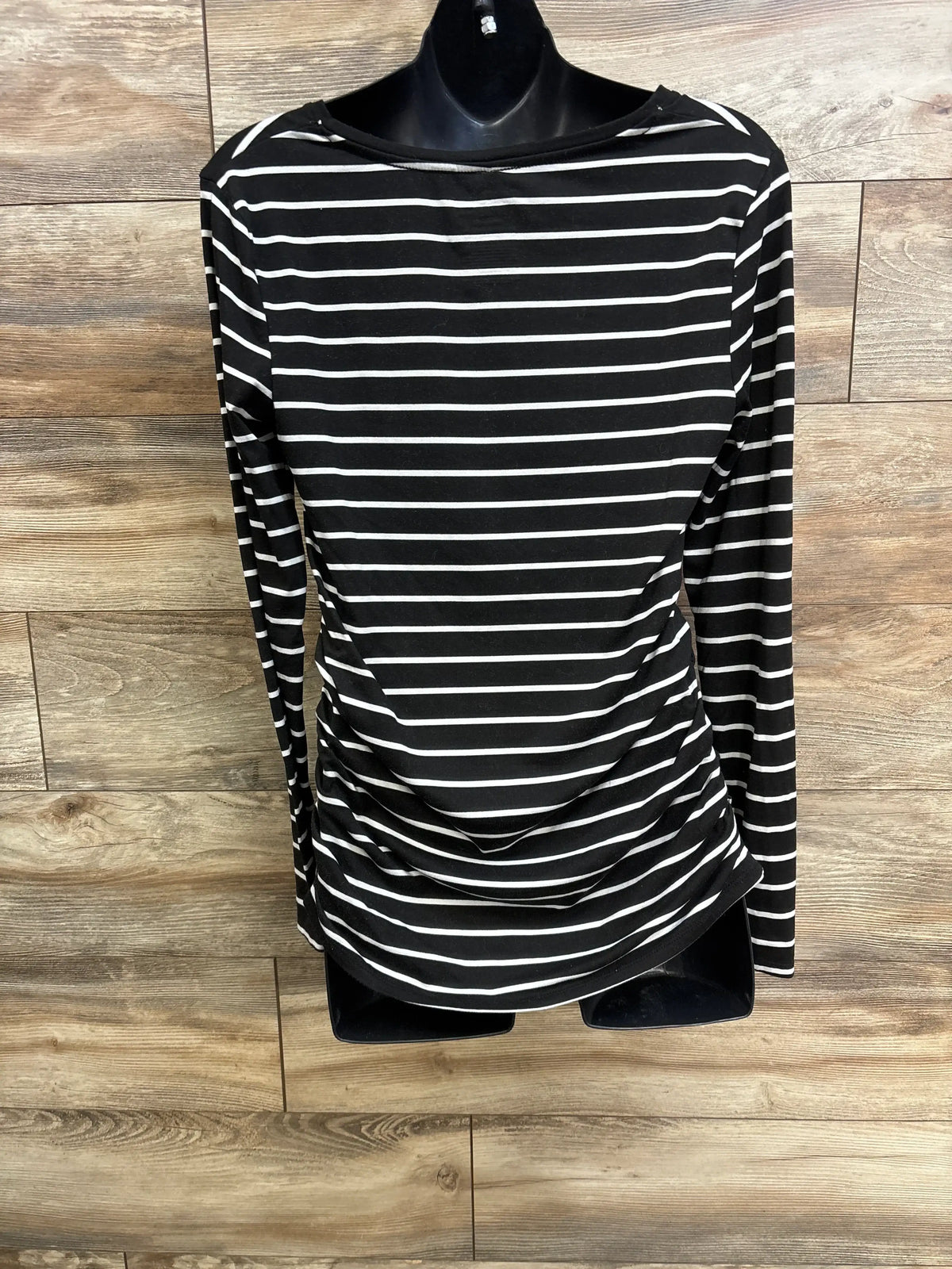 Front view of Time & Tru black striped maternity shirt showcasing long sleeves and side ruching with wood floor background
