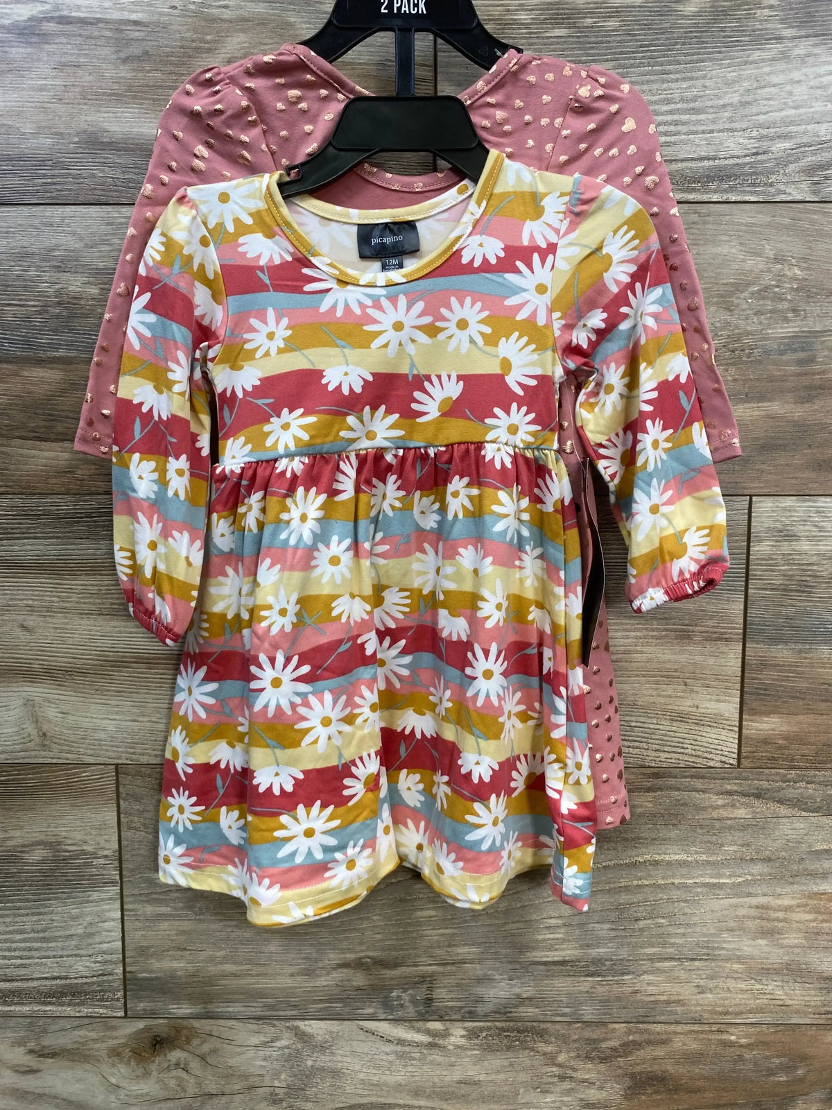 Two-pack baby girl dresses on hangers, one floral striped and one pink with gold heart accents