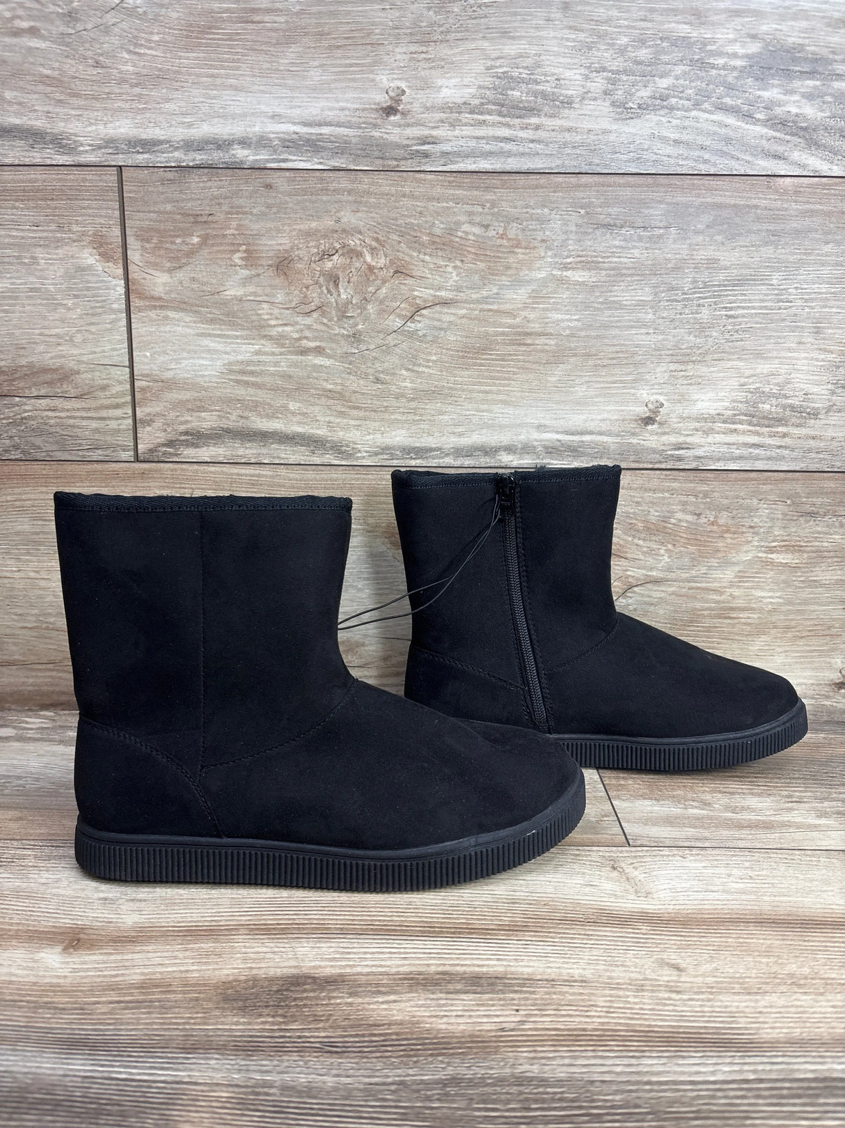 Black suede kids winter boots with side zipper on wood background