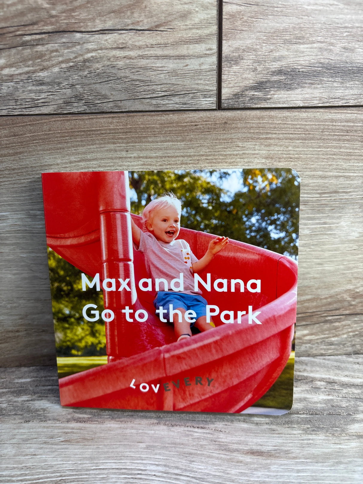 Children’s book titled 'Max and Nana Go to the Park' with a smiling toddler on a red slide
