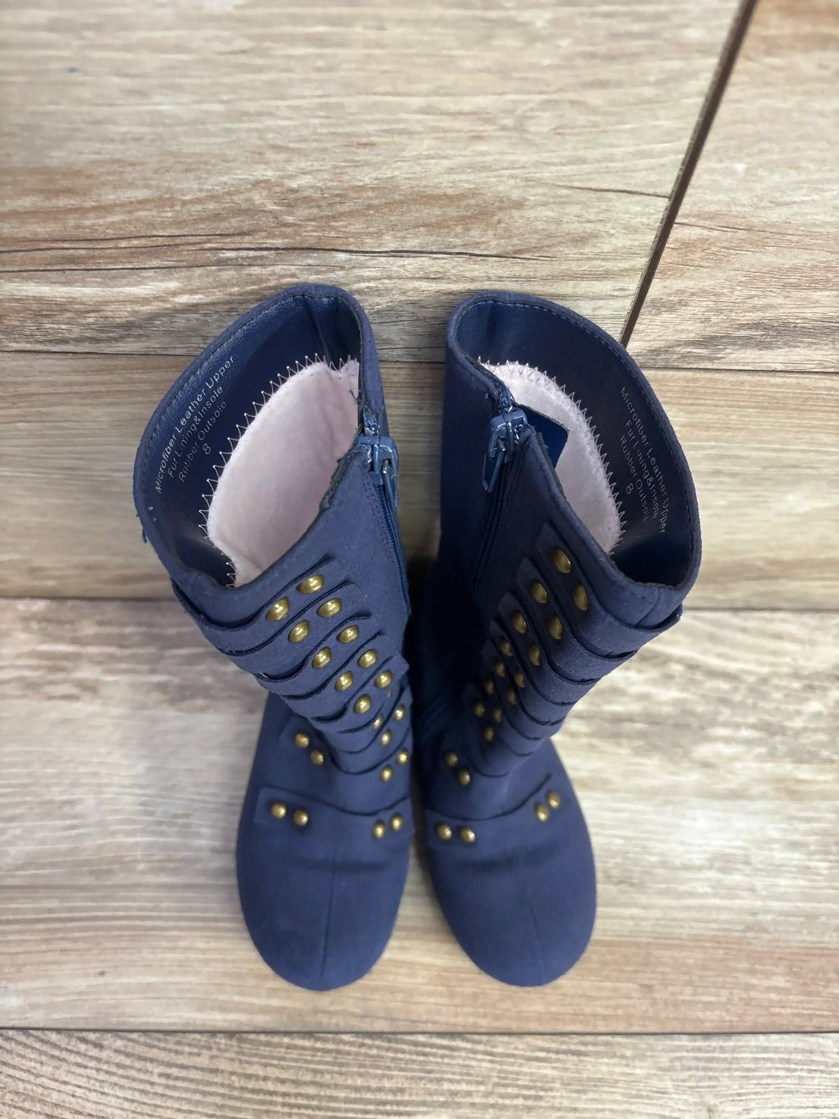 Top-down view of Liv and Mia navy toddler military-style studded boots size 8C showing gold studs and side zippers on wooden floor