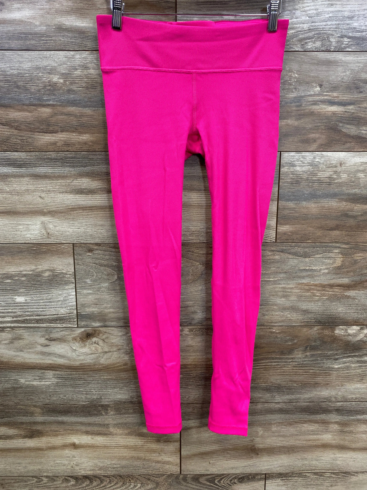 Front view of pink maternity leggings showing under belly rib panel and full length blackout fabric on wood plank background
