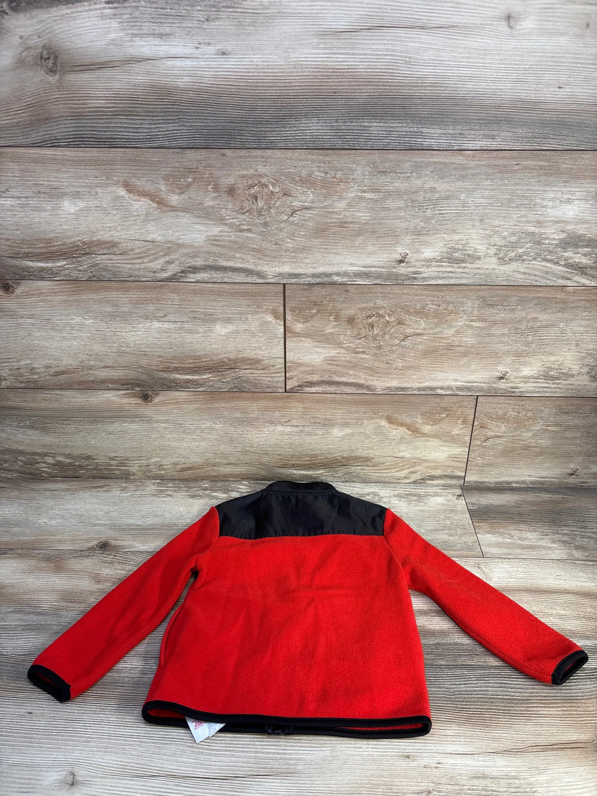 Back view of Disney Store Mickey Mouse fleece jacket (4T) showing red fleece body, black shoulder yoke and black trim on light wood floor