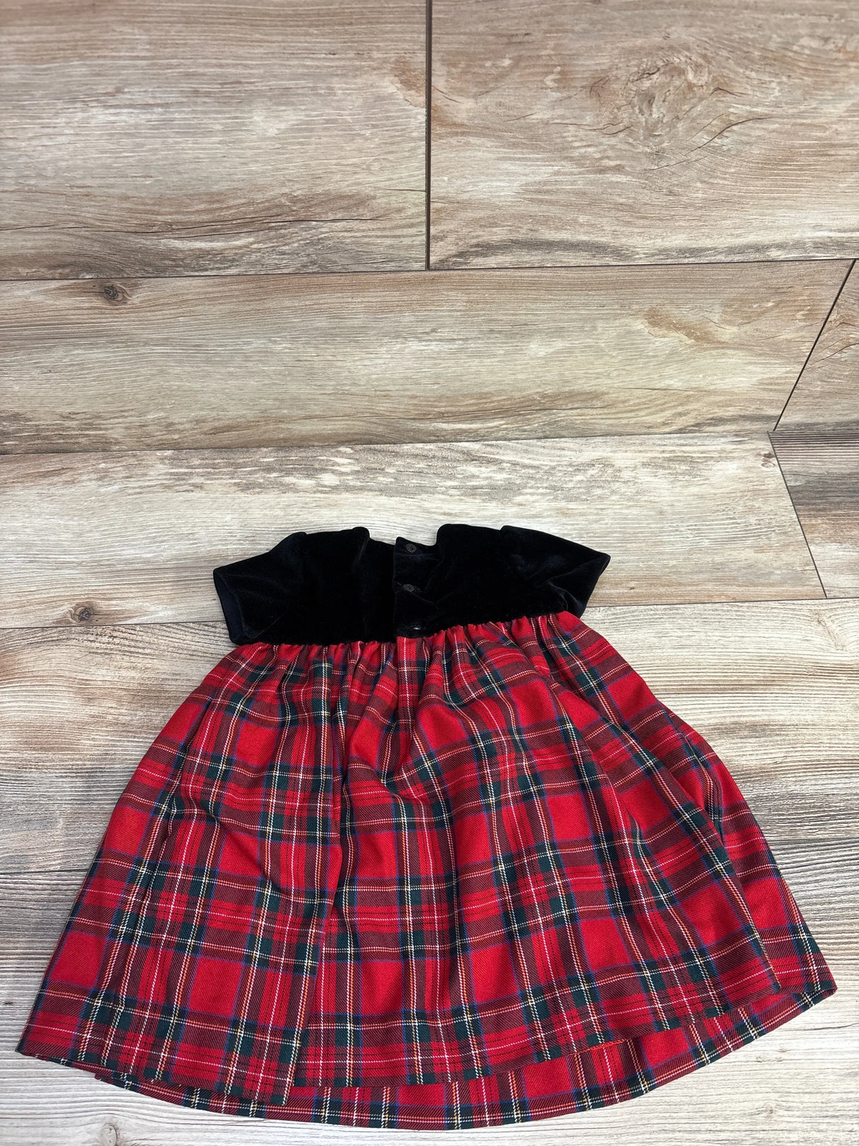 Red plaid girls dress with black velvet bodice displayed on wood floor