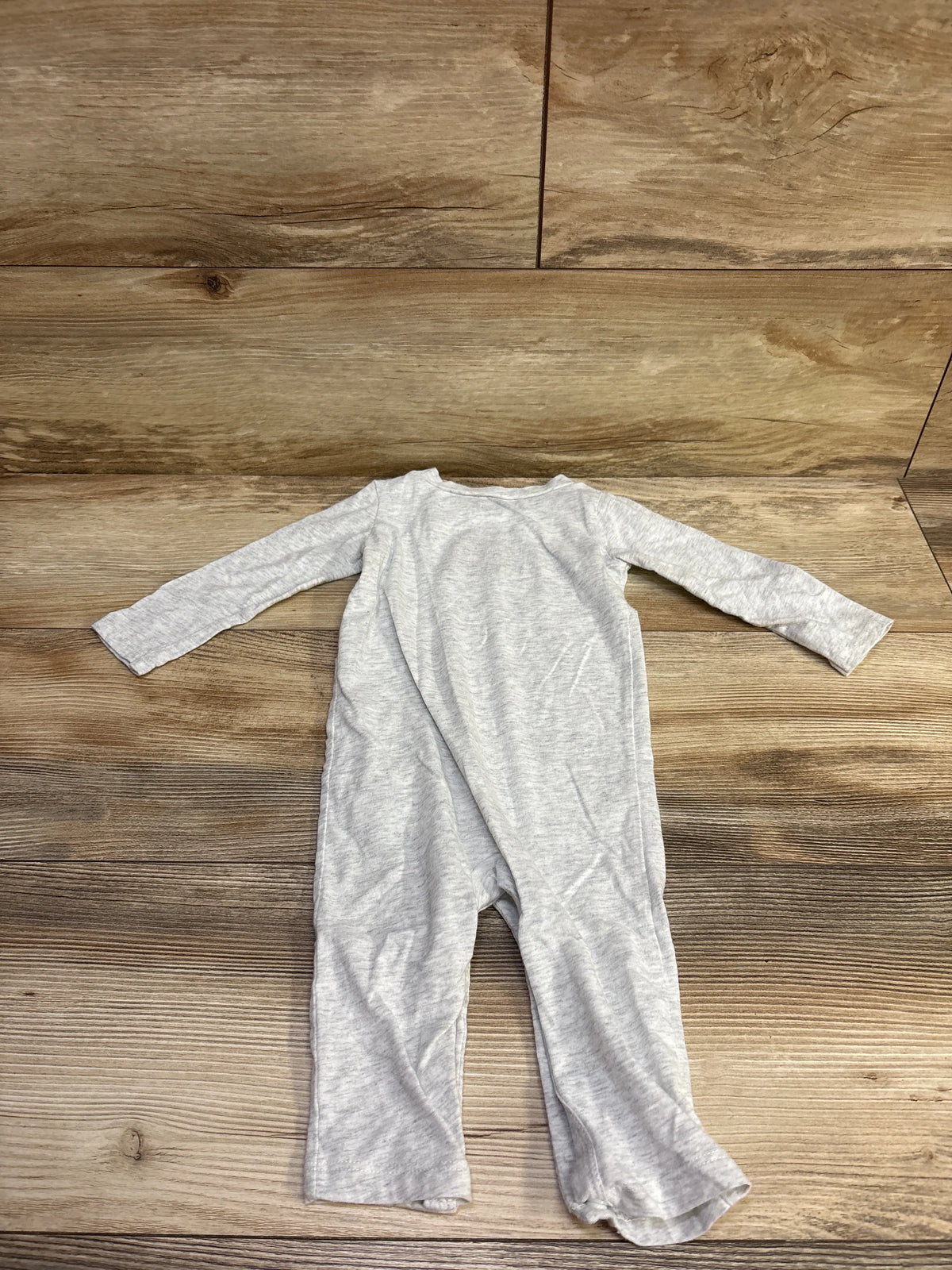 Flat-lay view of Nike grey coverall for 9 months showcasing long sleeves and full-length legs on a wood-look background