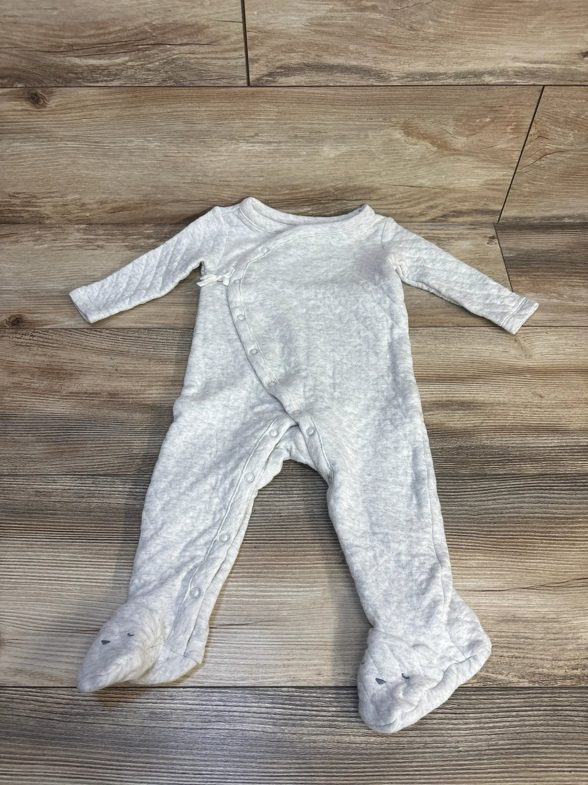 Light gray baby footed sleeper with animal face booties, long sleeves, on wood floor